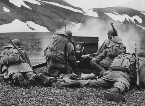 WWII soldiers behind gun with snowy hillside in the distance