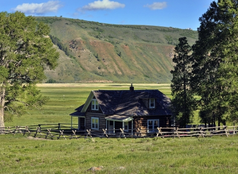 The historic Miller House at National Elk Refuge in Wyoming, with mountains behind it..