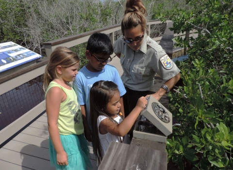 Supervisory Refuge Ranger Toni Westland joins kids exploring a scat panel on the Education Boardwalk Trail at J.N. "Ding" Darling National Wildlife Refuge in Florida.