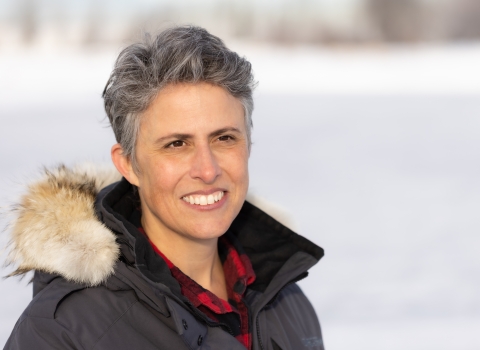 a woman in a coat with snow behind her