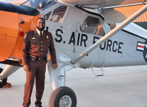 African American man stands in front of plane with "U.S. AIR FORCE" on side