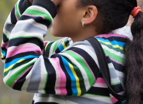 A young birder looks through binoculars