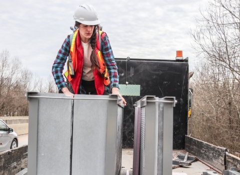 Person standing in the back of a flatbed truck examining artificial bat roosts