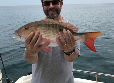 Scott Covington holding a fresh caught fish in his hands while out fishing. 