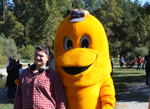 Student smiling next to Wolf Creek NFH's golden trout mascot, Goldie