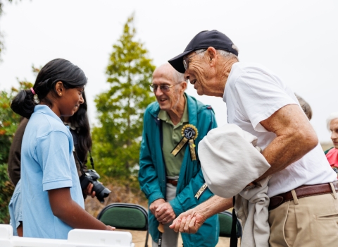 A young girl talks with a group of adults at an outdoor event