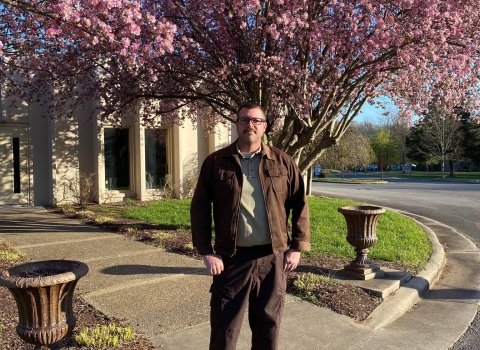 USFWS employee standing in front of blooming trees & building