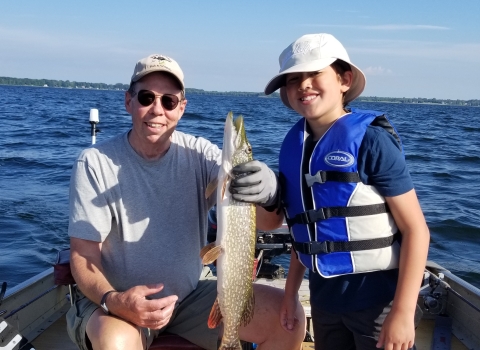 The author and his grandson in a fishing boat, holding a fish