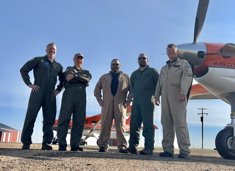 five people standing in front of an airplane