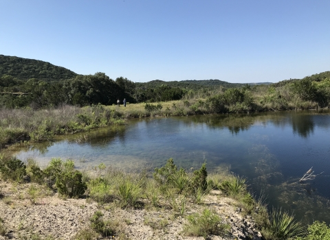 A large pool of water in a green, hilly landscape