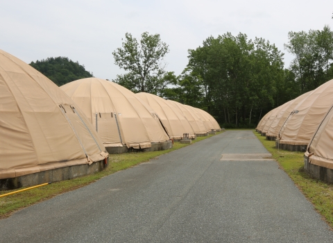 A paved road lined with circular, canvas-domed fish rearing tanks. 