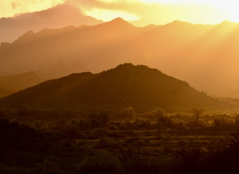 Sunrise over multiple layered mountain ranges.
