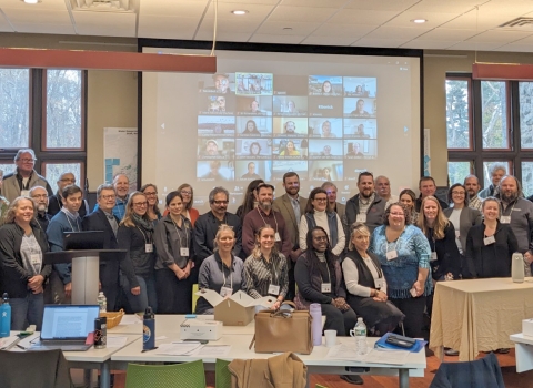 A group of people at a conference pose for a group photo. 