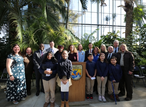 Group photo of adults and youth smiling. A U.S. Fish and Wildlife Service logo can be seen on a podium in the center of the photo