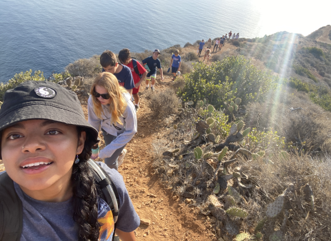 A woman taking a selfie with a line of hikers behind her