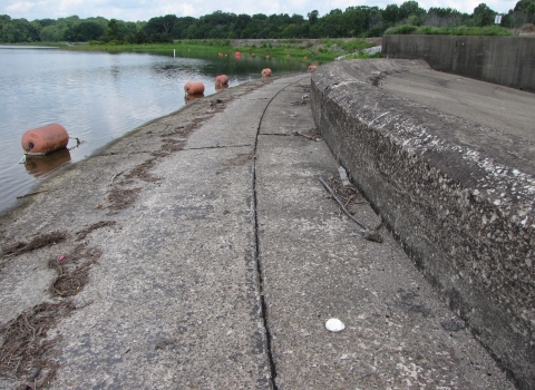 Curved cement infrastructure with green trees and a lake in distance