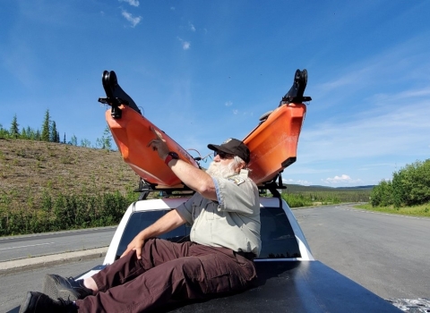 Watercraft inspector physically inspecting two kayaks on top of truck roof rack for aquatic invasive species.