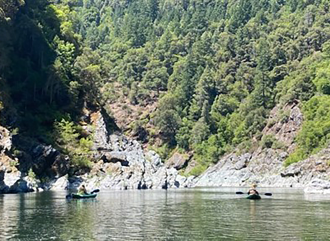 A group of people kayaking on a lake with mountains in the background