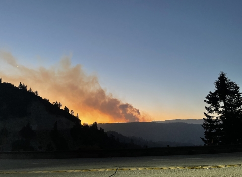 a smoke plume emerges from a mountain at sunrise