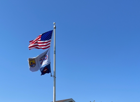 3 flags on flagpole with US flag atop USFWS ones