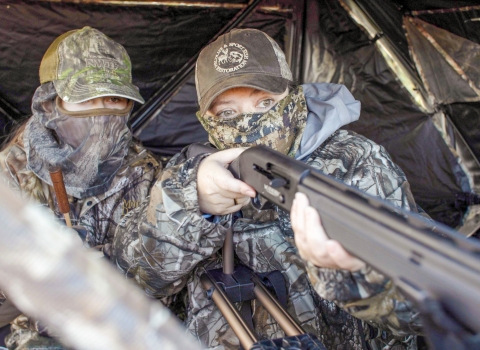 Two hunters in camouflage waiting in a hunting blind